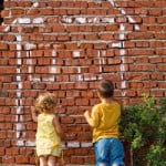 children drawing with chalk on a brick wall