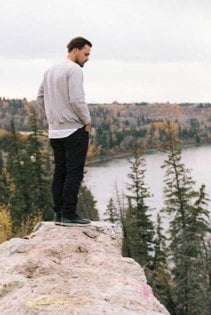 Man standing on cliff looking down at trees