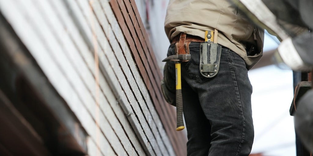 Worker wearing black denim and carrying a hammer in a holster