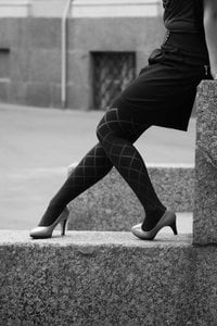 body of a woman in heels leaning on a wall