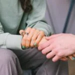 Close up of two people holding hands, comforting each other
