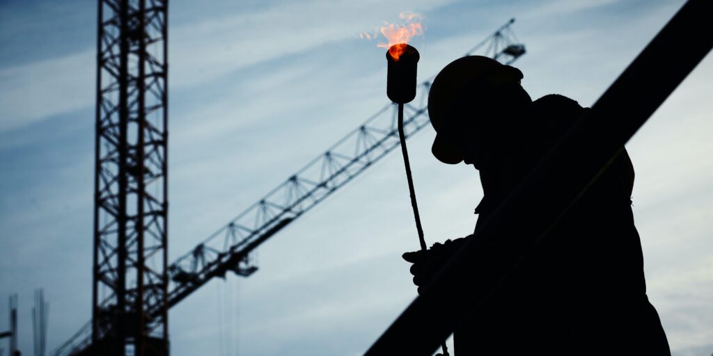 Dark image of worker on a construction site with a crane in the background