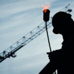 Dark image of worker on a construction site with a crane in the background