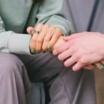 View of two pairs of hands, with one person comforting the other.