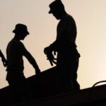 Silhouette of 3 workers under a white sky