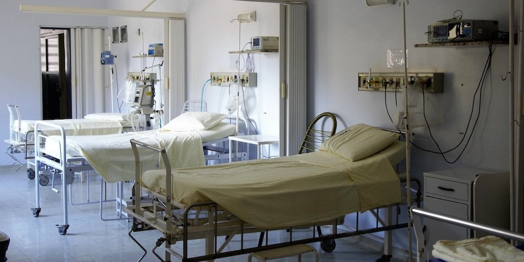 Three empty hospital beds in a hospital room