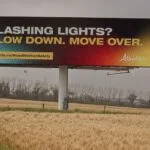 Billboard along a highway with the following message from the Government of Alberta: "Flashing lights? Slow down. Move over."