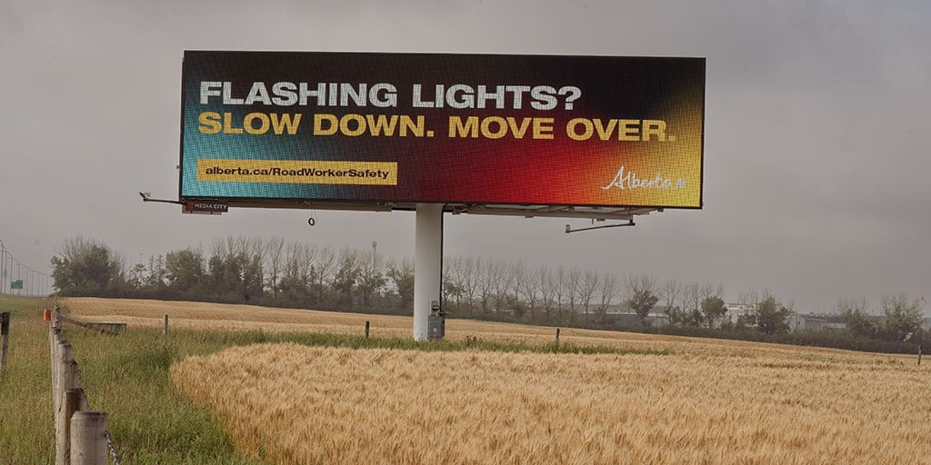 Billboard along a highway with the following message from the Government of Alberta: "Flashing lights? Slow down. Move over."