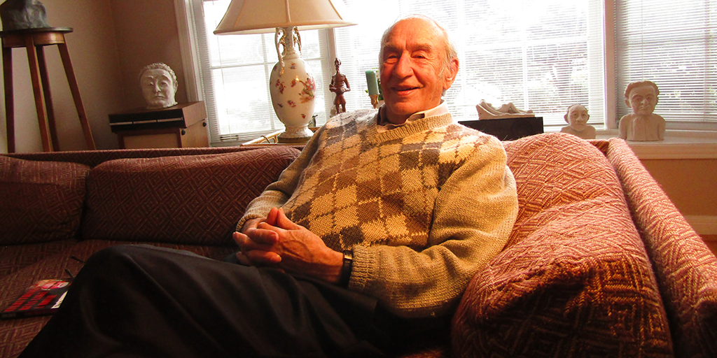 Photo of Hart Pomerantz sitting casually on a couch and smiling at the camera
