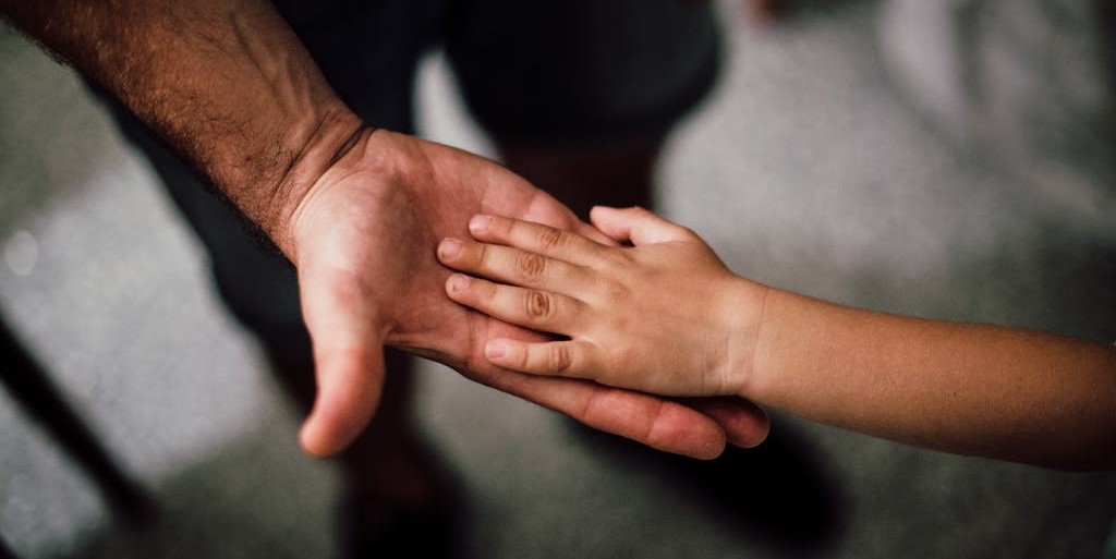 Child's hand face down on top of adult's hand face up