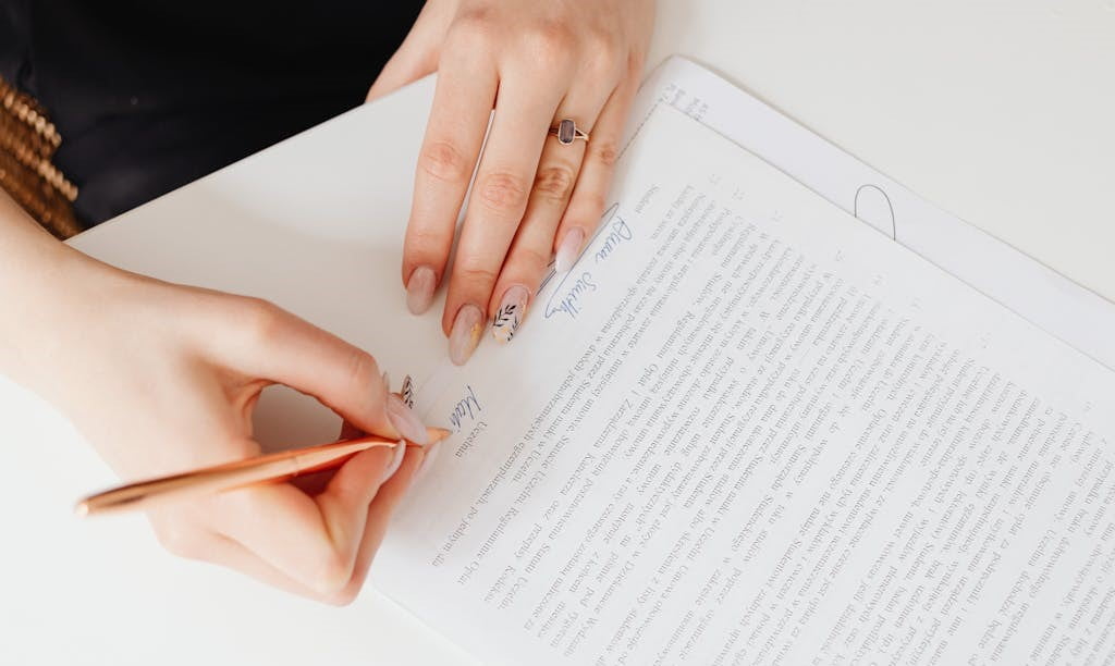 A person's hands are shown signing an official looking document with a pen.