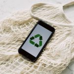 Mobile phone with green recycling sign and mesh bag